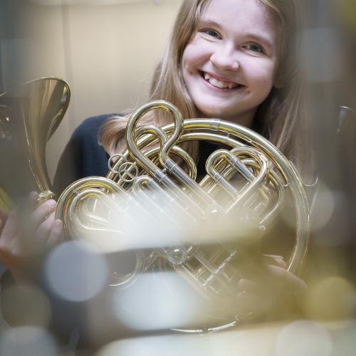 Student of the Brass Academy holding a French horn.